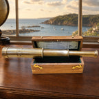 12 inch Dollond London brass telescope with wooden box on a desk overlooking a harbour